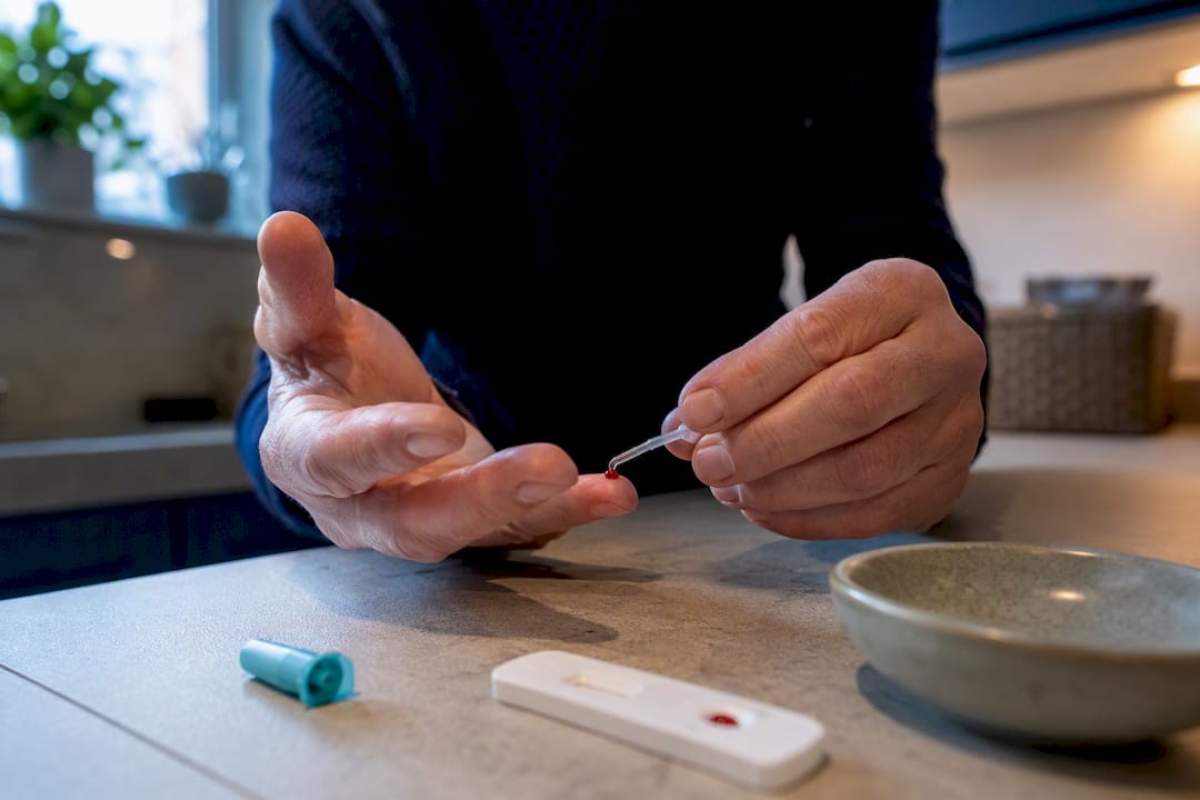 Hands applying blood sample to PSA test strip